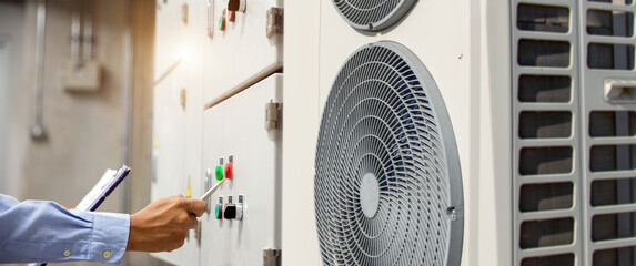Electrical engineer checking electric at circuit breaker of air handling unit (AHU) starter control panel for air conditioner or load center cabinet for maintenance in main power distribution room.