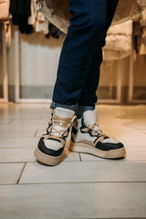 A persons legs wearing shoes, specifically sneakers or walking shoe 5869s.