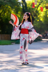 Young women wearing traditional Japanese kimono or yukata is happy and cheerful in the park.