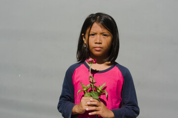 Alone female child holds flowers to her chest