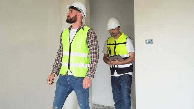 team of Construction workers Senior architect or civil engineer and foreman walking and discussion to inspection structure interior apartment with tablet at construction site. Electrical plug hole