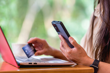 Woman's hands holding a credit card and using smart phone and laptop for online shopping, online payment. Digital banking, internet payment, online shopping, financial technology concept.