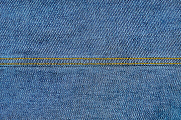 Texture of blue denim jeans fabric with orange seams