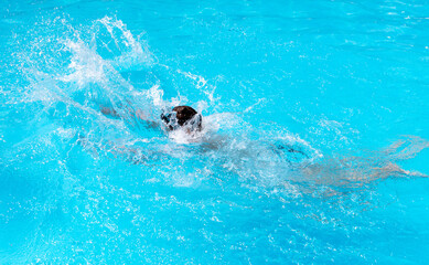 A teenage boy swims in the blue water of a pool