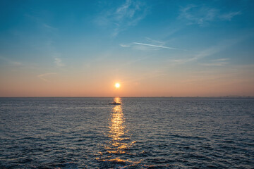 small fishing boat going in the open sea at sunset