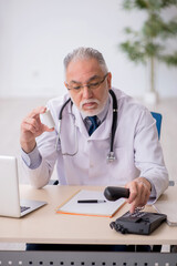 Obraz premium Old male doctor suggesting pills in the clinic