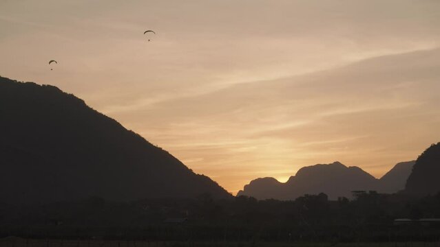 A powered parachute at Vang Vieng, Laos during sunset with a backdrop of karst mountains