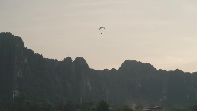 A powered parachute at Vang Vieng, Laos during sunset with a backdrop of karst mountains