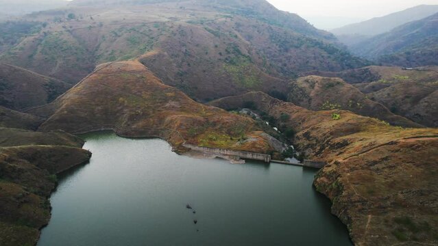 aerial drone orbiting a barrage shot flying over Alsigarh lake Rayta bahubali aravalli hills just outside udaipur a fast growing tourist spot in the city of lakes tourist spot in Rajasthan India shot