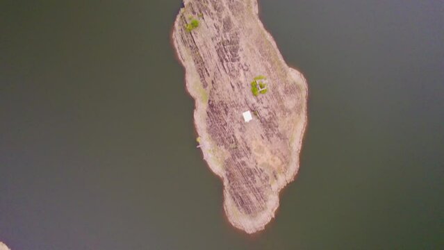 aerial drone shot shooting straight down small island in middle of lake with white house shot at Alsigarh rayta aravalli hills near Udaipur Rajasthan a fast growing tourist spot