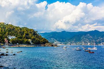 Obraz premium Fishing boats moored on water in harbor of Ligurian and Mediterranean Sea near coastline of Riviera di Levante of National park Cinque Terre Coast with blue sky, Riomaggiore village, Liguria, Italy.