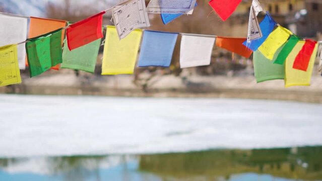 Closeup shot of Buddhist prayer flags above the frozen Nako Lake during the winter season at Nako village in Kinnaur, Himachal Pradesh, India. Prayer flags above the frozen lake on way to Spiti Valley