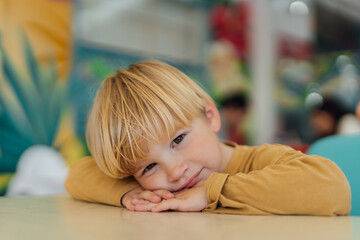 Fototapeta premium boy sitting on chair at the table, his head resting on his hands