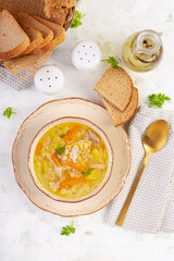 Fresh chicken soup with vegetables and stelline pasta in a bowl with carrot and parsley. Top view, flat lay