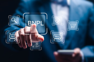 BNPL or Buy Now Pay Later concept, Businessman use smartphone with virtual BNPL icon with online shopping icons technology.