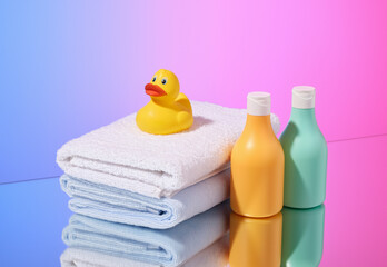 Obraz na płótnie Canvas Shower gels, towels and a yellow rubber duck. Baby care and hygiene accessories.