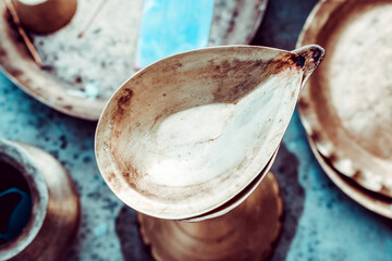 A bronze lamp stands among the puja utensils