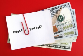 An amount of cash dollars money clipped with a white note pad written INVEST IN YOURSELF, concept...