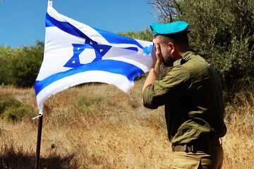 Memorial Day for Israel Fallen Soldiers. IDF fighter mourns near the Israeli flag in memory of his...