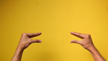 Men's hands with a gesture of two people talking on a yellow background
