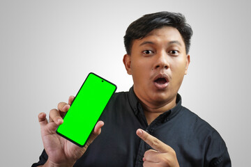 An Asian man is displaying the contents of his smartphone screen with a green screen display at a diagonal angle.