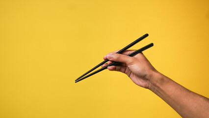 Man's hand pointing finger at camera on yellow background