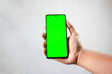 The green smartphone screen is held in the right hand