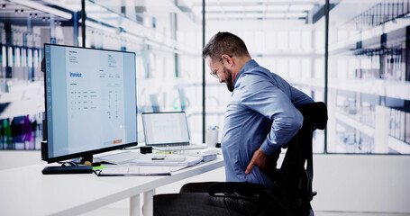 Side View Of Accountant Suffering From Back Pain At Desk