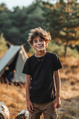 Caucasian kid in plain black blank t-shirt at camping with tents in background