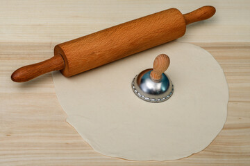 Ciasto na pierogi leży obok drewnianego walka, wycinać okrągły kształt 