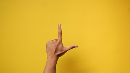 Man's hand with index finger up and thumb gesture on yellow background