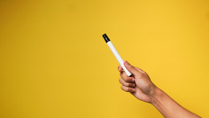 Man's hand holding a black marker on a yellow background