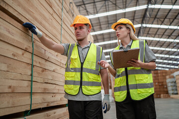 Engineer team standing walking in warehouse examining hardwood material for wood furniture production. Technician man and woman working on quality control in lumber pallet factory. Worker check stock