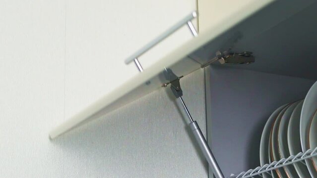 Footage of the man opening kitchen cabinet. Household