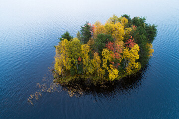 An aerial of a small island with colorful trees during autumn foliage in Northern Finland