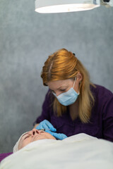 The cosmetologist performs needle mesotherapy on the client's face.