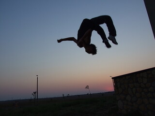 guy doing a backflip in parkour style at sunset