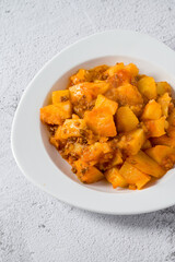 Minced meat and potato dish on white porcelain plate on stone table