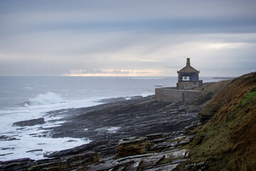 Fototapeta na wymiar House on a cliff next to wild sea