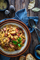 Cooked cabbage with sliced sausage on wooden table
