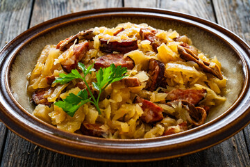 Cooked cabbage with sliced sausage on wooden table
