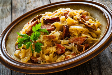 Cooked cabbage with sliced sausage on wooden table
