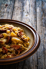 Cooked cabbage with sliced sausage on wooden table
