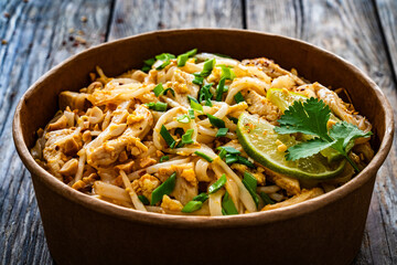 Pad Thai with chicken nuggets and rice noodles in peanut and tamarind sauce on wooden table in eco...