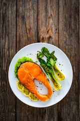 Fried salmon steak with lemon and steamed pak choi cabbage served on wooden table

