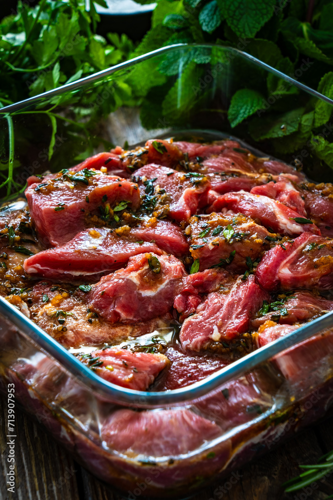 Wall mural Raw pickled pork cheeks in heat-resistant dish on wooden table

