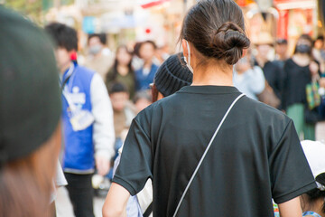 Fototapeta premium 髪を後ろでセットしたマスクを着用した黒いTシャツの一人の若い女性の後ろ姿