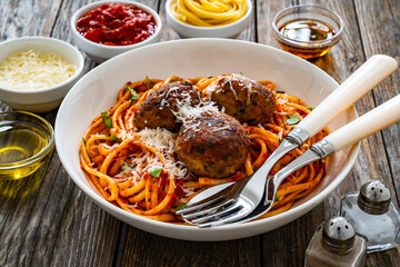 Spaghetti meatballs in tomato sauce on wooden table
