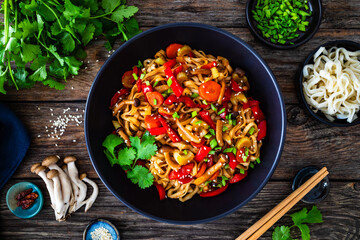Asian style stir fried vegetables and noodles on wooden table
