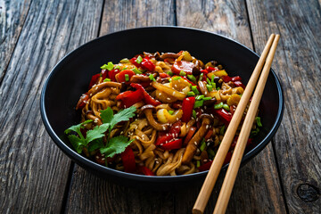 Asian style stir fried vegetables and noodles on wooden table
